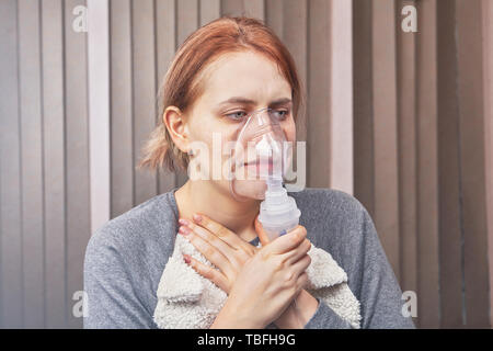 Junge Frau hat einen Asthmaanfall und nutzt Vernebler Kammer für Patienten mit interstitieller Lungenerkrankung, es zu stoppen. Stockfoto