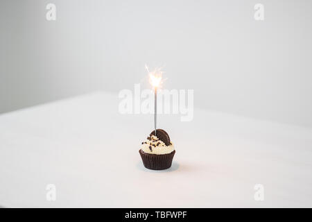 Essen, Party und Urlaub Konzept - Geburtstag Cupcake mit Wunderkerzen auf weißem Hintergrund mit Kopie Raum Stockfoto