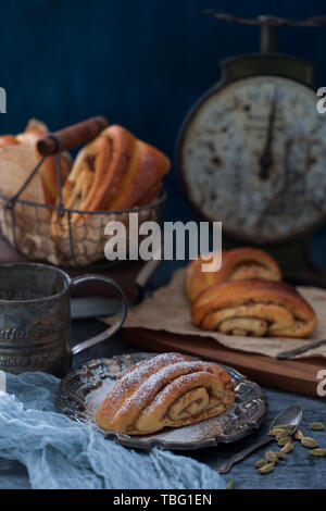 Finnische traditionelle Cinnamon Roll Brot auf Korvapuusti Hintergrund ist Europäischen und Amerikanischen Stil Eisen besteck Dekoration dunklen Ton Stockfoto