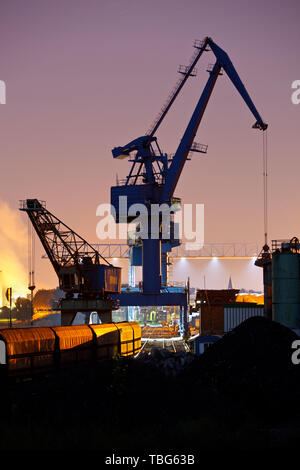 Nacht Blick auf Eisenbahnschienen, einem Bahnhof und einem großen Kran in einer Kohle Hafen. Stockfoto