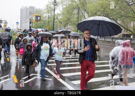 Touristen kommen aus der Brooklyn Bridge auf der Manhattan Seite, einem beliebten touristischen Spaziergang in New York City an einem regnerischen Frühlingstag. Stockfoto