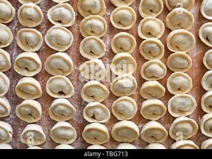 Hausgemachte russische Knödel, die Maultaschen, in Mehl auf der Holzplatte abgedeckt Stockfoto