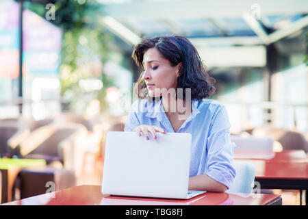 Betrachtet junge Frau im Cafe mit Laptop Stockfoto