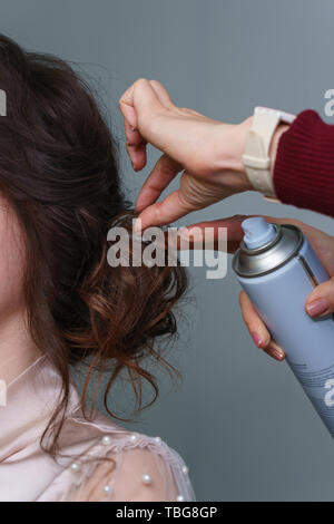 Erstellen Bild der Braut. Meisterwerk. Master stylist macht Braut Hochzeit Frisur mit Spray Lack zur Festsetzung Stockfoto