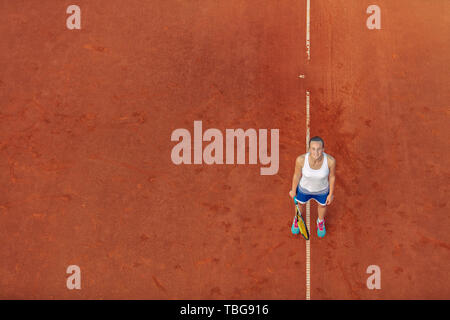 Luftaufnahme eines weiblichen tennis player auf einem Hof bei übereinstimmen. Junge Frau Tennis spielen. Hoher Blickwinkel betrachten. Stockfoto