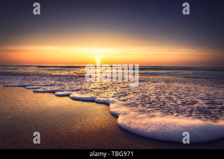 Sonnenaufgang über dem Meer und Strand. Wellen Waschen der Sand. Stockfoto