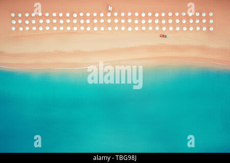 Antenne top Aussicht auf den Strand. Regenschirme, Sand und Meer Wellen Stockfoto