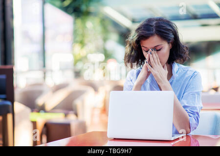 Betrachtet junge Frau im Cafe mit Laptop Stockfoto