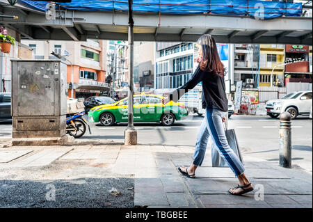 Ein junges thailändisches Mädchen macht sich auf den Weg über die belebte überlastete Sukhumvit Road im Nana-Gebiet von Bangkok Thailand. Stockfoto