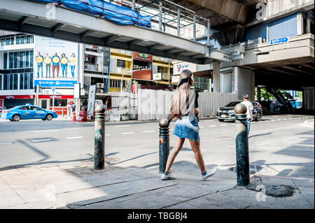 Ein junges thailändisches Mädchen macht sich auf den Weg über die belebte überlastete Sukhumvit Road im Nana-Gebiet von Bangkok Thailand. Stockfoto