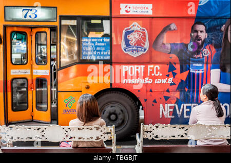 Die Menschen warten an einer Bushaltestelle an der belebten Sukhumvit Road in Bangkok. Stockfoto