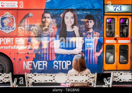 Die Menschen warten an einer Bushaltestelle an der belebten Sukhumvit Road in Bangkok. Stockfoto