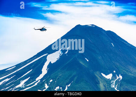 Hubschrauber fliegen über Kurile Ilyinsky Vulkan und See Stockfoto
