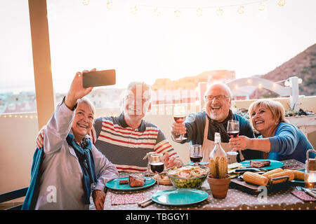 Happy Senioren Freunde unter selfie mit Mobile Smartphone kamera Barbecue Dinner - reife Menschen Spaß essen und trinken Rotwein auf der Terrasse Stockfoto