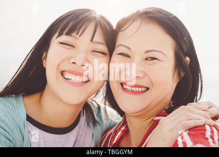 Asiatische Mutter und Tochter umarmen Outdoor - Glückliche chinesischen Familie genießen Zeit außerhalb - Elternschaft, Liebe und Menschen lifestyle Konzept Stockfoto