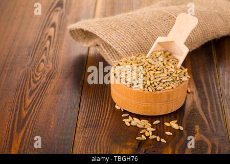 Rohstoff Roggen in einer Schale auf einem Holztisch und Sackleinen Stockfoto