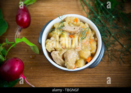 Geschmorte Kartoffeln mit Gemüse, Kohl und Fleisch in eine Schüssel geben. Stockfoto