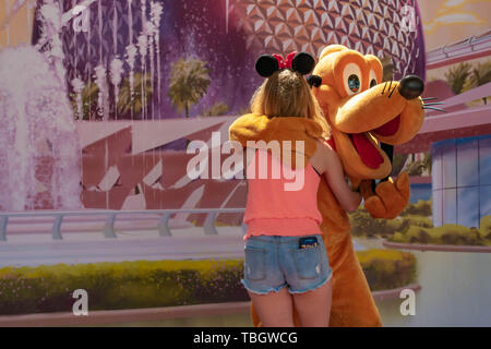 Orlando, Florida. März 27, 2019. Pluto umarmte Mädchen in Epcot in Walt Disney World. Stockfoto