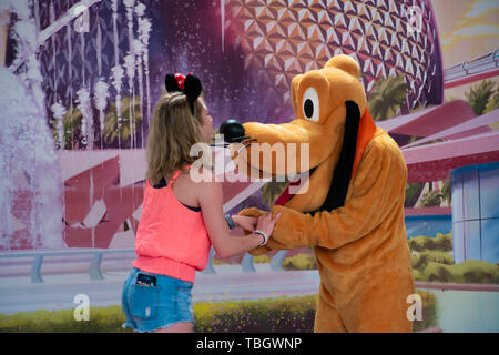 Orlando, Florida. 27. März 2019. Pluto unter den Händen der Mädchen in Epcot in Walt Disney World. Stockfoto