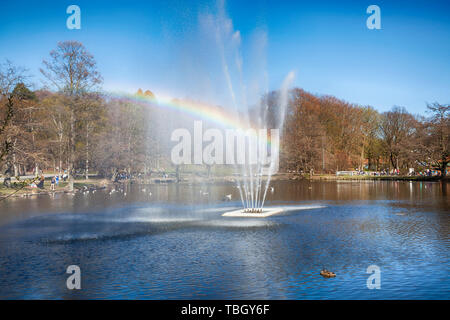 Regenbogen durch einen Brunnen in einem Teich in einem Park an einem sonnigen Tag an der Slottsskogen Park, Göteborg, Schweden Stockfoto