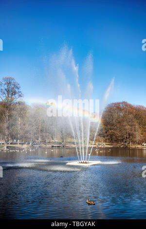 Regenbogen durch einen Brunnen in einem Teich in einem Park an einem sonnigen Tag an der Slottsskogen Park, Göteborg, Schweden Stockfoto