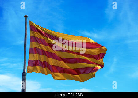 Die katalanische Flagge mit der Pole im Wind gegen einen blauen Himmel mit Wolken Stockfoto