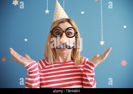 Lustige Frau mit Partei Dekor für April Fools' Day auf farbigen Hintergrund Stockfoto