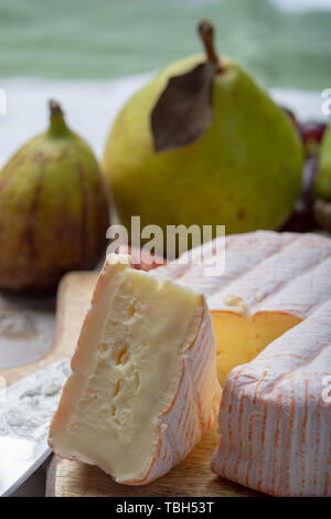 Rundes Stück französischer Käse Fleur Rouge aus Kuhmilch hergestellt als Dessert serviert mit frischen Feigen und Birnen Nahaufnahme Stockfoto