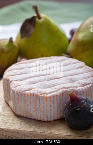 Rundes Stück französischer Käse Fleur Rouge aus Kuhmilch hergestellt als Dessert serviert mit frischen Feigen und Birnen Nahaufnahme Stockfoto