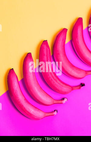 Nahaufnahme von rosa Bananen auf purpurfarbenem und gelbem Hintergrund, Ansicht von oben. Abstrakte, kreativ, Kreativität, Konzept Stockfoto