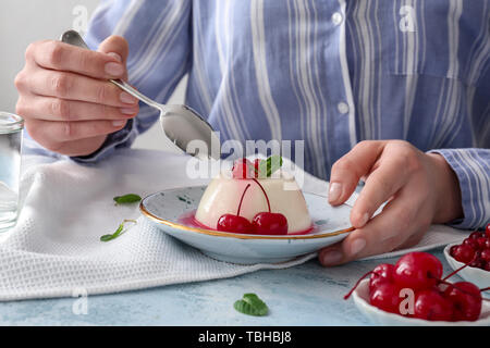 Frau essen lecker Panna cotta am Tisch Stockfoto