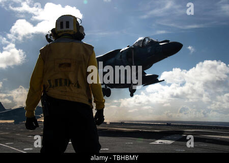 190529-N-PX 867-1928 PAZIFISCHER OZEAN (29. Mai 2019) der Luftfahrt Bootsmann Mate (Handling) 3. Klasse Roderick Willis, von Gary, Ind., zugeordnet zu den Amphibious Assault ship USS Boxer (LHD4), Signale ein AV-8B Harrier zu Marine Medium Tiltrotor (VMM) 163 Squadron (Verstärkt) nach einem Flug über mit zwei US-Air Force B-52 Stratofortress Flugzeuge zu 23 Expeditionary Bomber Squadron zugeordnet zu landen. Der Boxer Amphibious Ready Group (ARG) und 11 Marine Expeditionary Unit (MEU) werden in den USA 7 Flotte Bereich im Einsatz der regionalen Stabilität zu unterstützen, Partner und Verbündeten beruhigen, Stockfoto