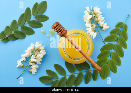 Honig im Glas und akazie Blüten auf blauem Hintergrund, Ansicht von oben Stockfoto