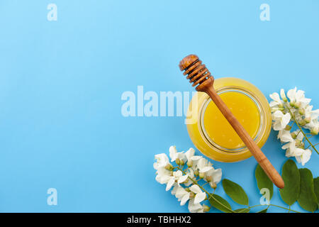 Honig im Glas und akazie Blüten auf blauem Hintergrund, Ansicht von oben Stockfoto