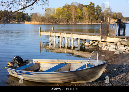 Aluminium-Boot neben einem hölzernen Steg in Styrmansholmen, Karlsudd, in der Nähe von Vaxholm, Schweden, während eines späten Frühlingnachmittag Stockfoto