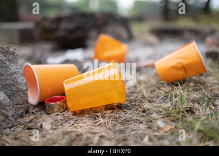 Orange einweg Kunststoff Glas oder Becher für Trinkwasser in einem Fach - Umweltproblem Konzept verwendet. Nicht kompostierbare Abfälle. Nach einem Picknick.natur Stockfoto