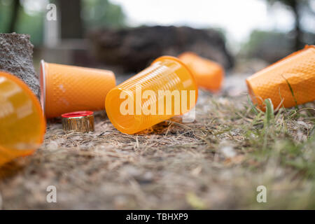 Orange einweg Kunststoff Glas oder Becher für Trinkwasser in einem Fach - Umweltproblem Konzept verwendet. Nicht kompostierbare Abfälle. Nach einem Picknick.natur Stockfoto