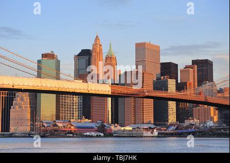 Brooklyn Bridge mit niedrigeren Skyline von Manhattan am Morgen mit bunten Wolken über den East River in New York City Stockfoto