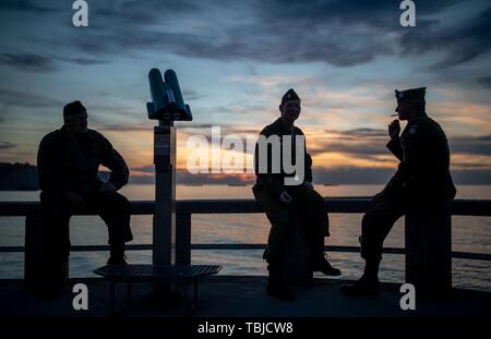 Arromanches-Les-Bains, Frankreich. 02 Juni, 2019. 01. Juni 2019, France (Frankreich), Arromanches-Les-Bains: Drei Männer aus Aachen sitzen in der ursprünglichen historischen uns in den Sonnenuntergang am Gold Beach Uniformen. Nach der Landung der alliierten Truppen eine der zwei künstliche Häfen (Mulberry B) gebaut wurde an der Küste von Arromanches-les-Bains, durch die Truppen und liefert an Land gebracht wurden. 06.06.2019 ist der 75. Jahrestag der Landung der alliierten Truppen in der Normandie (D-Day). Quelle: dpa Picture alliance/Alamy leben Nachrichten Stockfoto