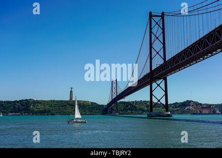 Die Brücke des 25. April (Ponte 25 de Abril) über den Tejo an der Küste von Lissabon. Links im Bild sehen Sie die Christus Statue (Cristo Rei). Die Brücke verbindet in nord-südlicher Richtung die Lissabonner Stadtteil Alcântara mit der Stadt Almada. | Verwendung weltweit Stockfoto