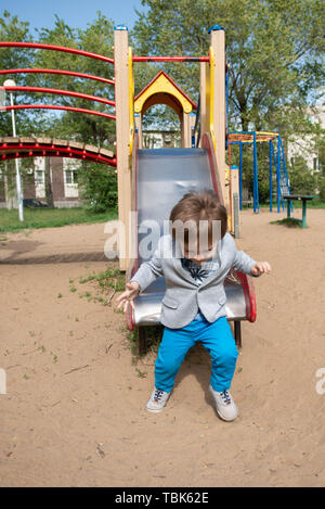 Junge auf dem Spielplatz Rollen einen Hügel hinunter Stockfoto