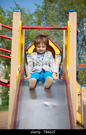 Junge auf dem Spielplatz Rollen einen Hügel hinunter Stockfoto