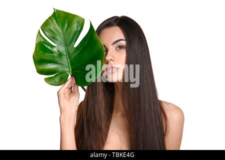 Porträt der schöne junge Frau mit gesunden langen Haaren Holding tropischen Blatt auf weißem Hintergrund Stockfoto