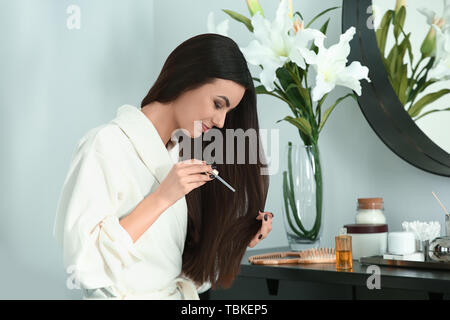 Schöne junge Frau serum Anwendung auf Ihre gesunde lange Haare zu Hause Stockfoto