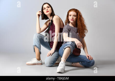 Portrait von modischen jungen Frauen auf grauem Hintergrund Stockfoto
