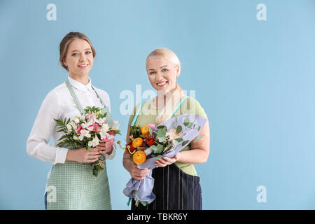 Weibliche Floristen mit blumensträussen auf farbigen Hintergrund Stockfoto
