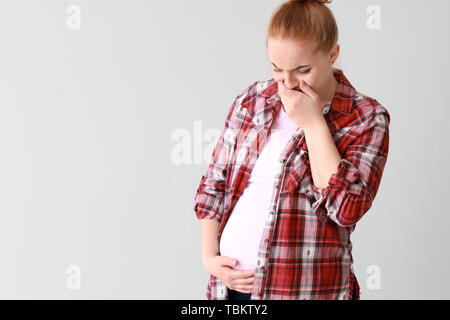 Junge schwangere Frau mit toxicosis auf hellen Hintergrund Stockfoto