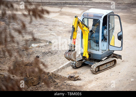 Verfolgt mini bagger bricht aus alten bordsteine vor dem Einbau der neuen Bordsteine. Das Konzept der Verwendung wirtschaftliche und kompakte Geräte für die Bedürfnisse der Städte. Stockfoto