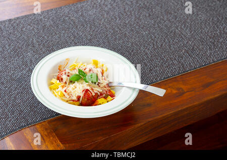 italienische Pasta Bolognese mit Basilikumblättern und Parmesankäse Stockfoto