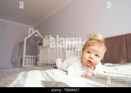 Ein neugeborenes Baby liegt auf dem Bauch in der Baumschule auf dem Bett. Stockfoto